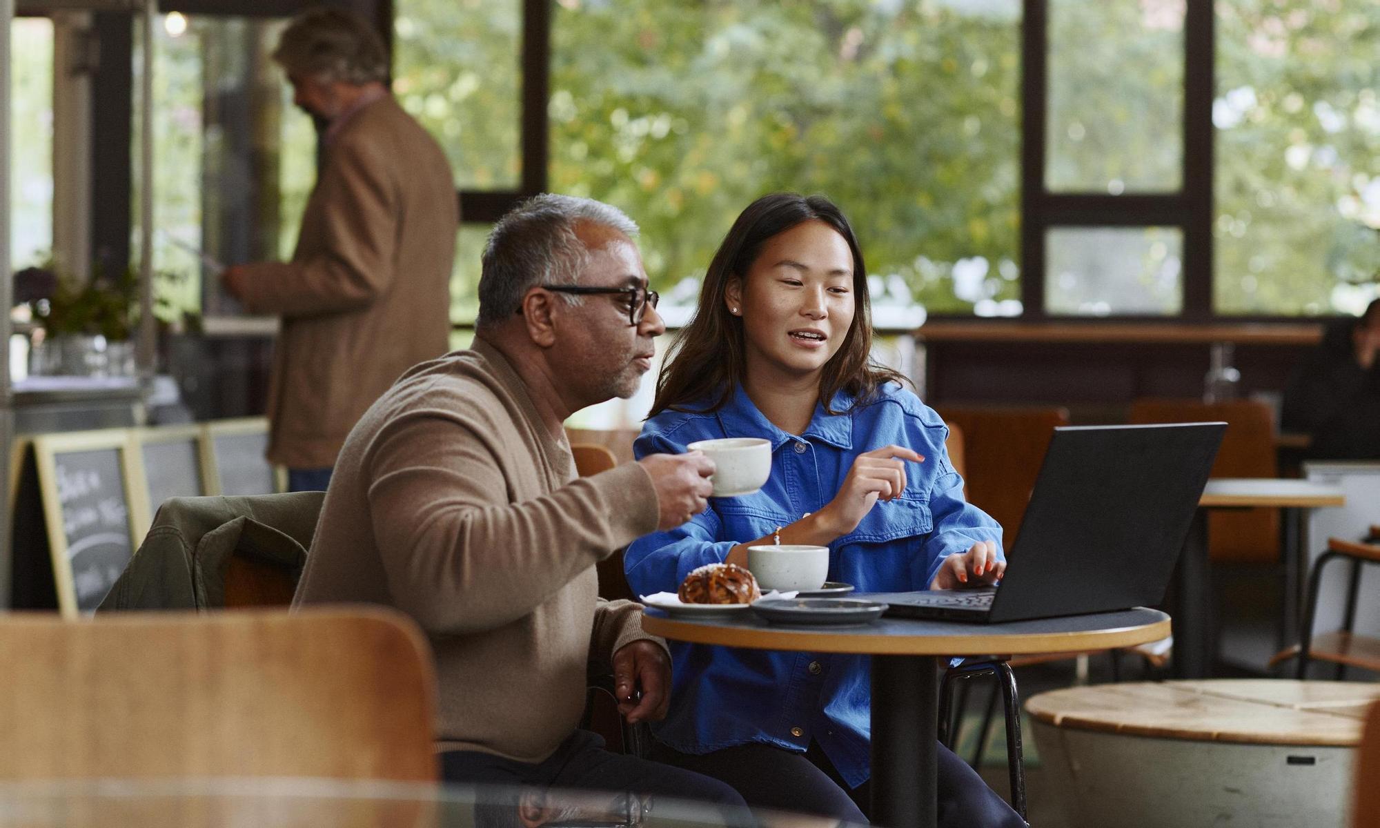 Two people in a café looking at a laptop 