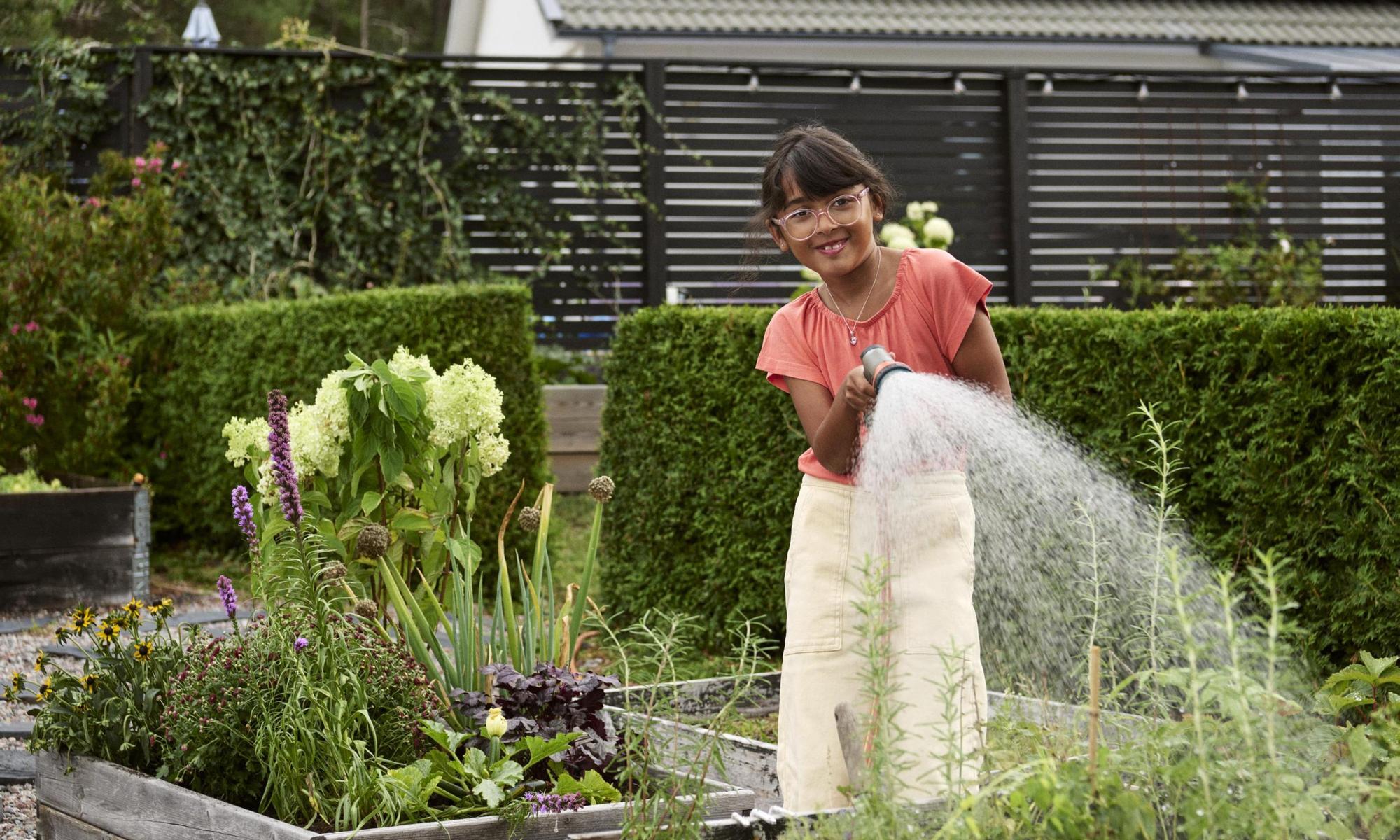 Girl watering the kitchen garden. Solar panel in the background
