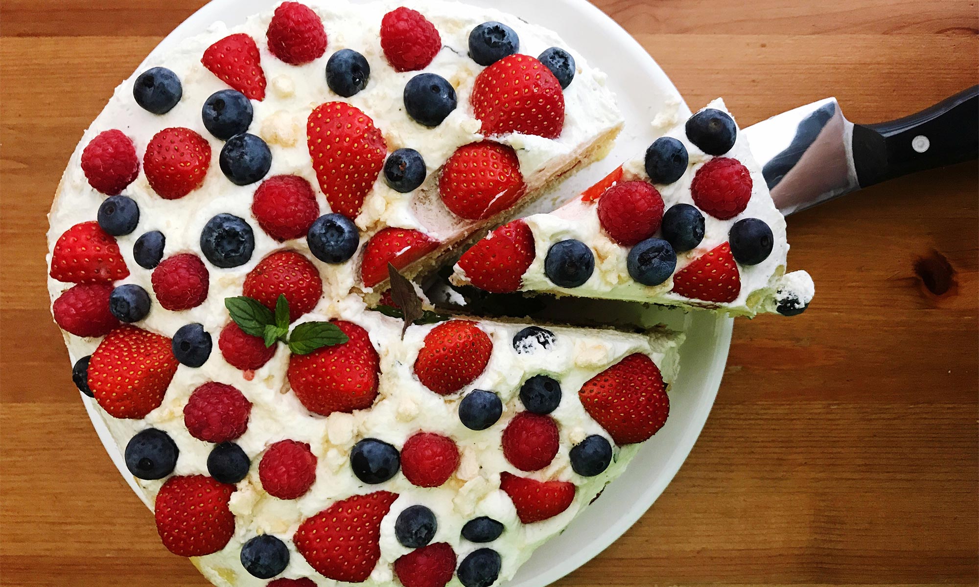 Sommrig tårta med jordgubbar och blåbär på ett bord